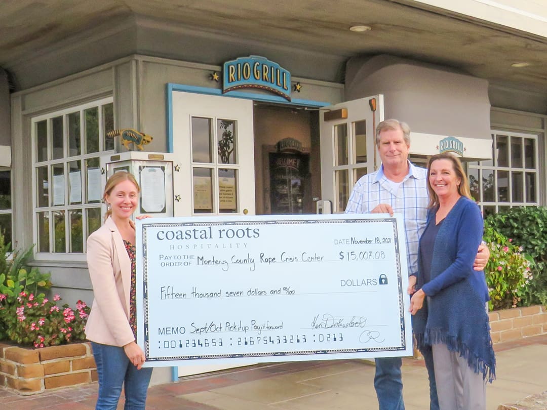 Three people hold a large check.