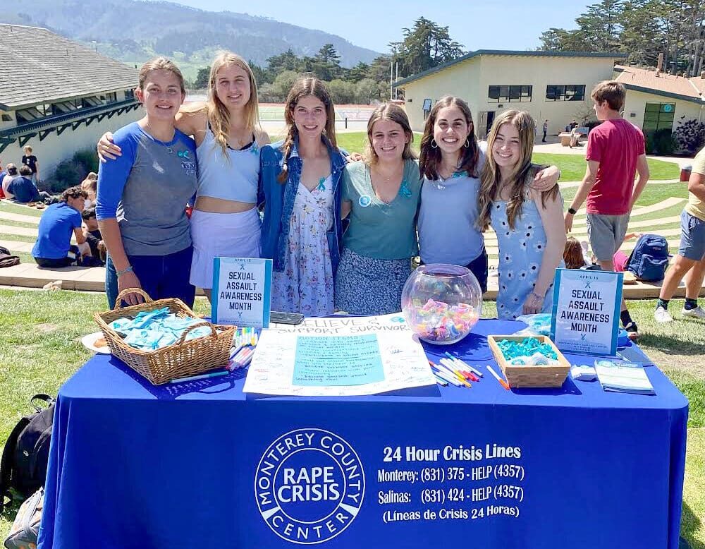 A group of females behind a booth stand.